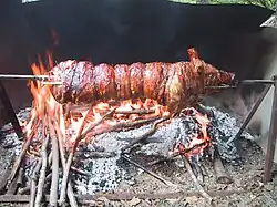 Piglet being spit-roast over open wood fire