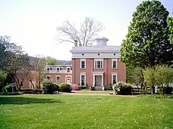Red mansion with a wing on the left and a grassy lawn in front