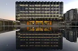 A glass building overlooking a manmade body of water