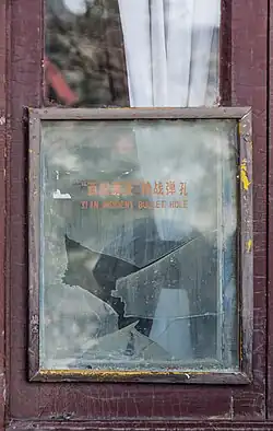 A window pane with a bullet hole surrounded by cracks