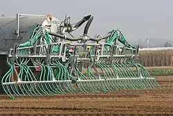 System of tubes attached to the rear of a tractor on a field