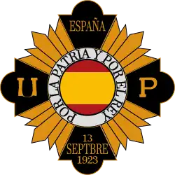 The yellow and black emblem of the Unión Patriótica. The Spanish flag is in the middle of the emblem, contained in a circle shape.