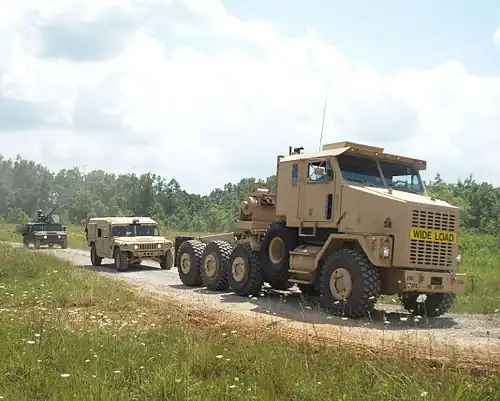 The relative size of the M1070 can be gauged against the Humvees following it.