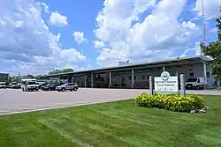 A sign to the right reads "MetroWest Regional Transit Authority - 15 Blandin Avenue", with a minibuses and various cars parked in a lot in the background, and a bus station in the background.