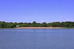 beach and trees viewed from across the lake