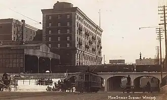 View of Main Street underpass of the railroad tracks beside a six-storey warehouse