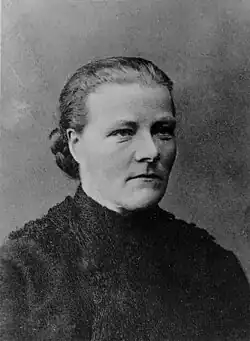 Black and white photograph of a Northern European woman with a dark fur jacket and hair pulled back into a braided bun