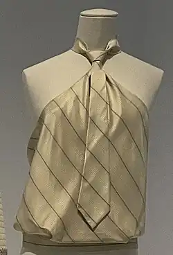 Beige halter top with thin black diagonal stripes and a men's tie on the front