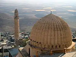 Picture of a dome of a mosque in the foreground set against a misty cityscape with a minaret on the left side of the image.