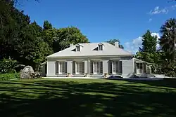 An old-fashioned house in a grassy and forested landscape