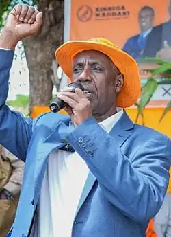 Mohamed Aw-Ali Abdi, wearing an orange hat, pumping his fist as he speaks into the microphone