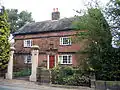 A sandstone house behind a pair of ornamental gateposts (which are listed separately)