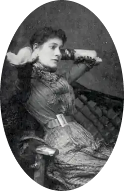 portrait of young white woman with dark hair, leaning back in a chair