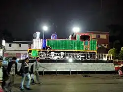 An abandoned narrow gauge steam loco is being displayed in front of old building
