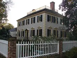 A two-story blue-grey colonial house with brick chimneys