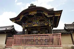 Black wooden gate with colorful ornamentation and a Chinese style gable on the front.