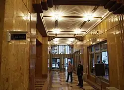 View of the lobby. The lobby is decorated with marble walls, plaster ceilings, and aluminum grilles, and there are ornamental lights on the ceiling.