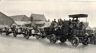 A battery of howitzers on the move. Note the gun crew members riding on the artillery tractor and seats on the gun carriage.