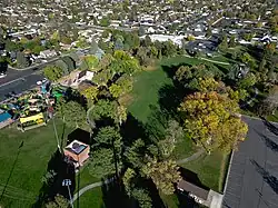 An aerial photo of the park showing the trees, some with orange leaves, with the houses in the background.