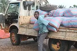 A young black man holds a sack against a pickup truck