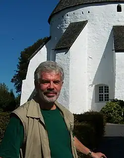 Ove von Spaeth in front of the historical Oesterlars round church on the Danish island Bornholm