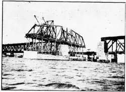 A truss swing bridge span being constructed in the middle of a river