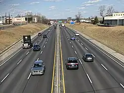 Straight, heavily traveled section of six-lane highway in suburban area