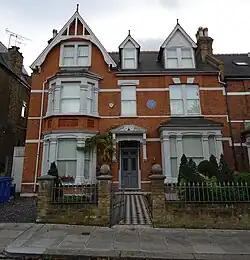 A large orange brick house with white windows and ornamentation
