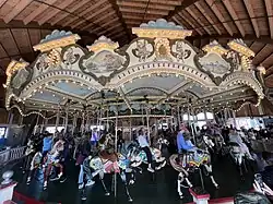 Carousel horses on a white historic carousel adorned with lights