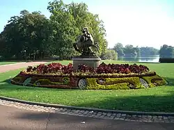 The statue on its pedestal surrounded by flowers in geometrical arrangements