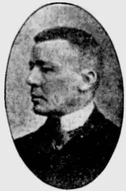 Black and white photo of a middle-aged man wearing a high-collar white dress shirt with a dark suitcoat