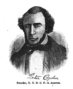 An image of Peter Ogden in a suit with a three links pin on his coat.