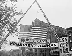 Photograph of U.S. flag and welcoming banner hung over a Washington street during ceremonies in honor of visiting Mexican President Miguel Alemán Valdés, 1947.