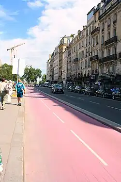 A dedicated two-way bike lane, painted in red asphalt, stands in between a street and a sideway