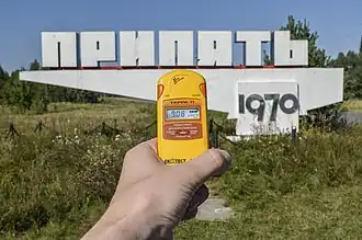 Pripyat city limit sign with a radiation dosimeter