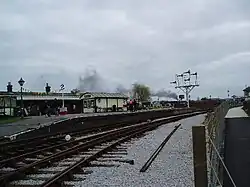 Curving concrete station platform. There is a small wooden hut on the platform.