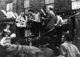 The Quarrymen performing in Rosebery Street, Liverpool, on 22 June 1957.[1] Left to right: Hanton, Griffiths, Lennon, Garry, Shotton and Davis.