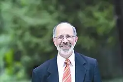 Shmuel Goldin wearing a suit while standing outside