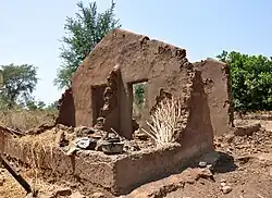 Mud walls standing in an empty area. The smooth surface is flaking off to show the interior of the walls.