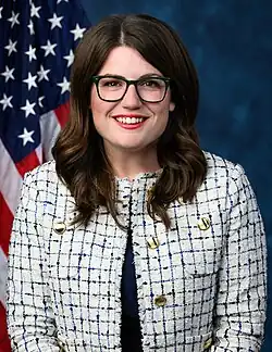 Official House portrait of Elfreth smiling in front of the U.S. flag, wearing a white and blue blazer jacket with gold buttons.