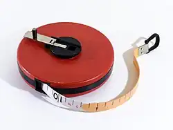 A cased measuring tape with a hand crank