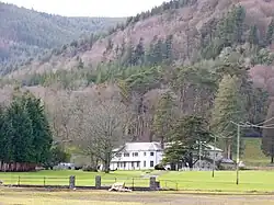 a white house in front of wooded hillside