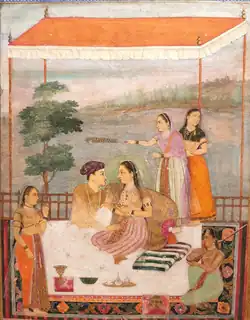 A man and a woman sitting on a platform, gazing at each other, while female attendants surroudn them