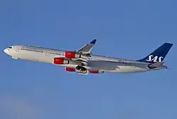 A large jetliner with a white body, four red engines and a blue tail
