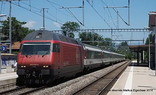 Red locomotive pulling coaches arrives at island platform
