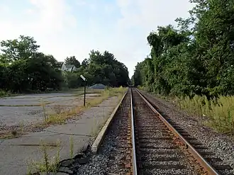A disused railway platform next to a single active track