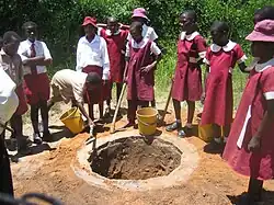 School children in Zimbabwe digging a shallow pit for an Arborloo toilet (a variation of a pit latrine), Epworth in Harare, Zimbabwe