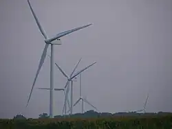 Five turbines of the Scioto Ridge Wind Farm in a zoomed narrow-angle shot, some of which are partially below the horizon due to distance and topography.
