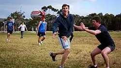 Scott Minto passing a football in a park