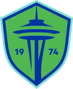 The Seattle Sounders FC crest, a green and blue shield with the shape of the Space Needle in the center and the year of the club's founding (1974).